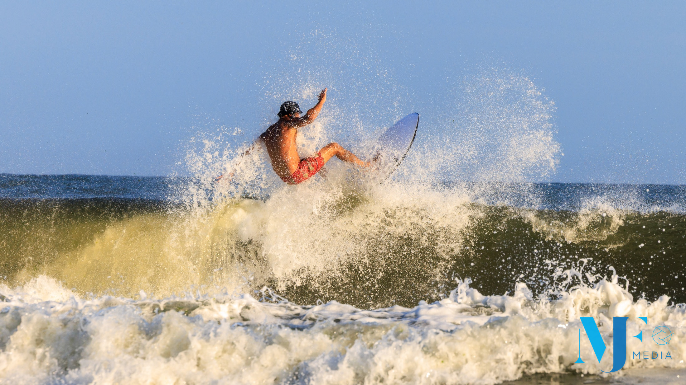 Surfer throwing spray above a breaking wave