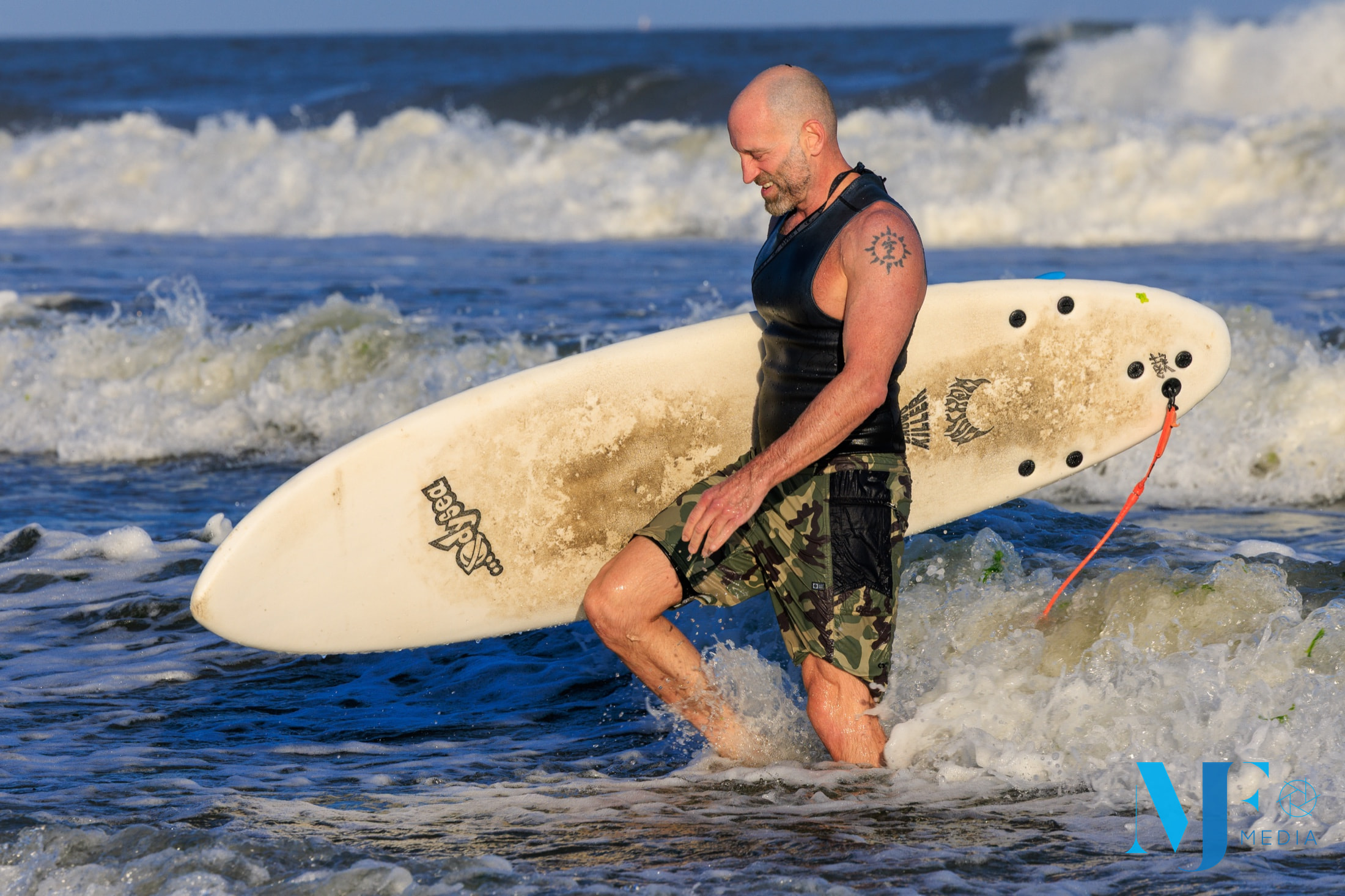 Surfer walking through the shorebreak with a longboard