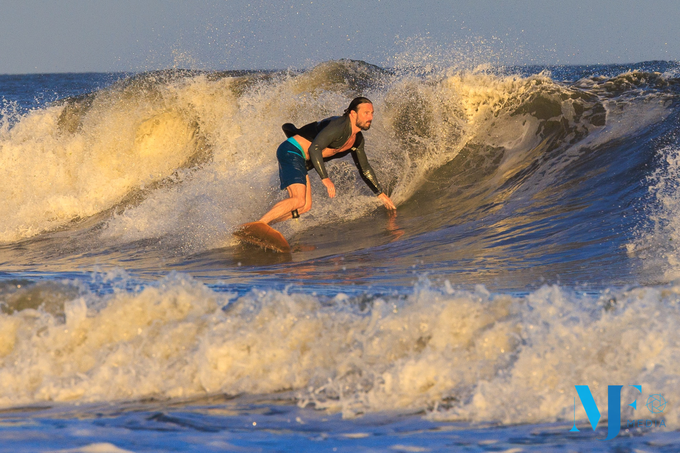 Surfer drawing a line through a golden Rockaway wave