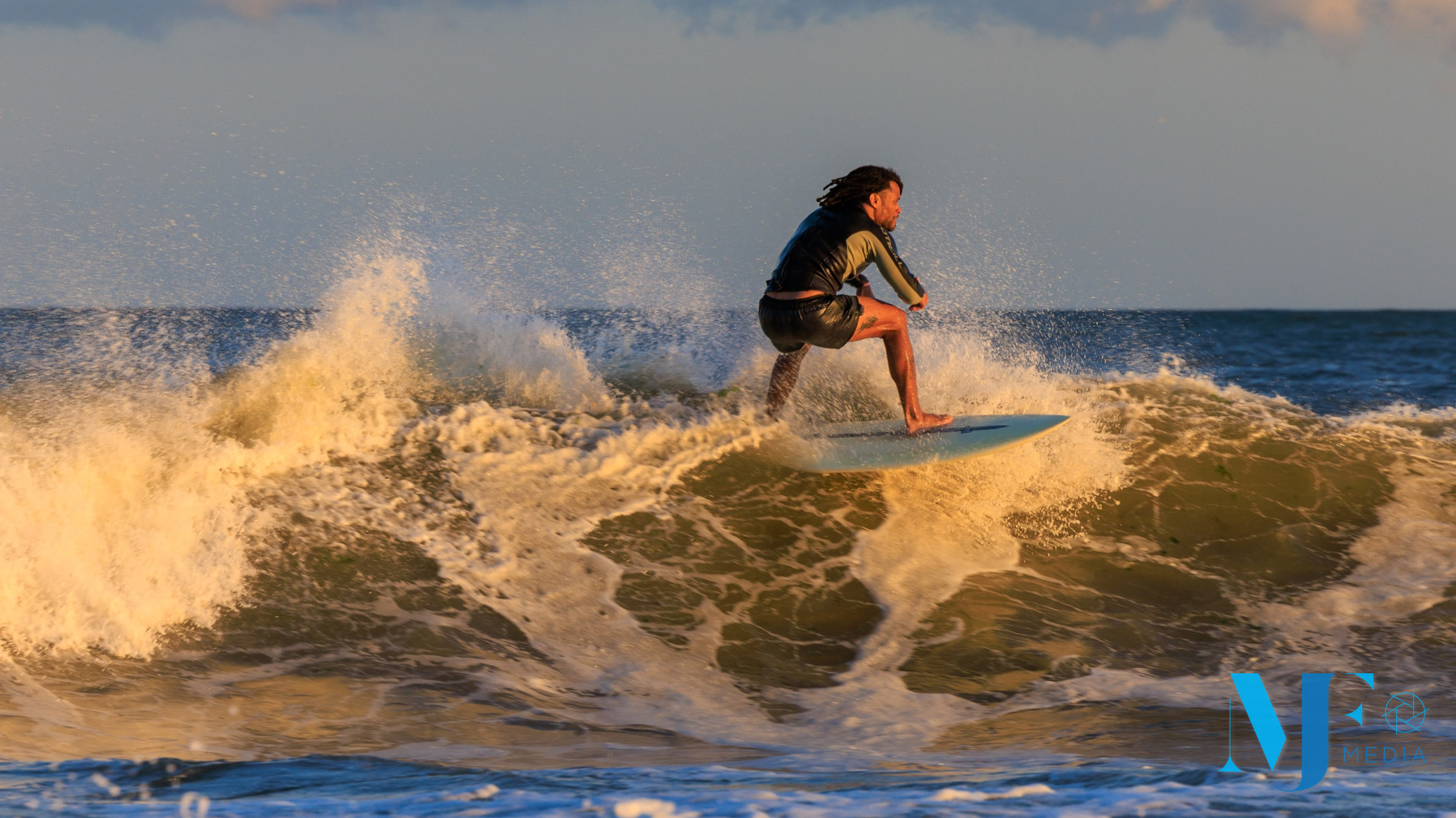 Surfer riding over a sunlit section of a wave